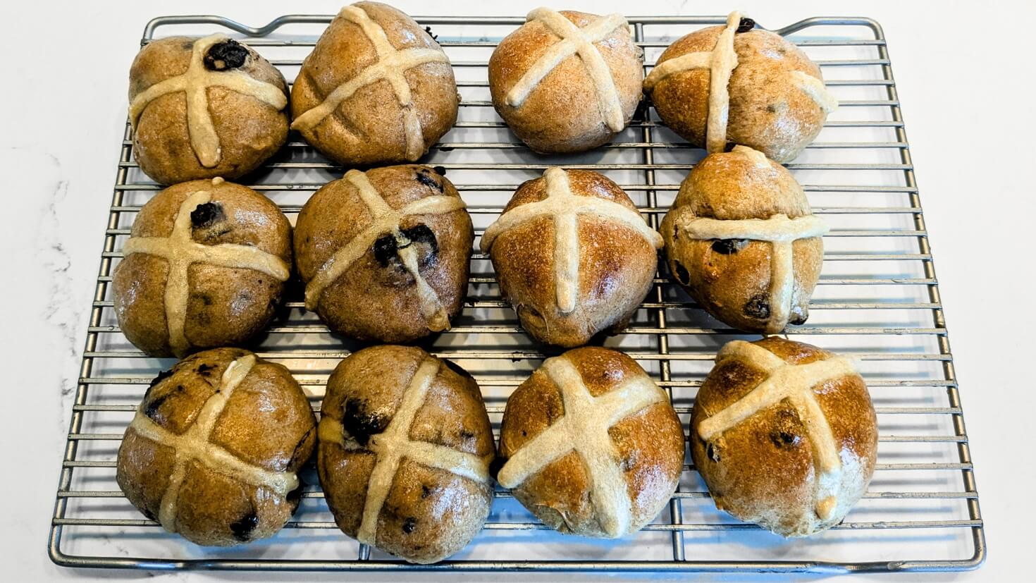 Sourdough hot cross buns cooling on a rack