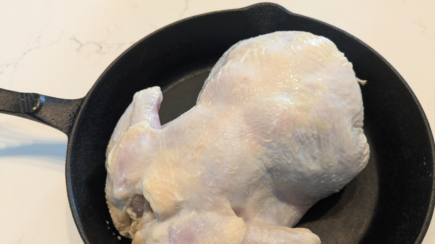 Raw buttermilk-marinated chicken in a cast iron skillet